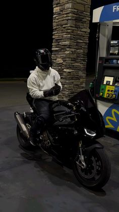 a man sitting on a motorcycle in front of a gas pump