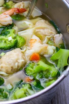 a pot full of soup with shrimp, broccoli and carrots