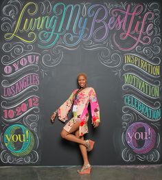 a woman standing in front of a chalkboard with the words living my life written on it