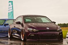 two cars parked next to each other on a wet parking lot in front of a sign