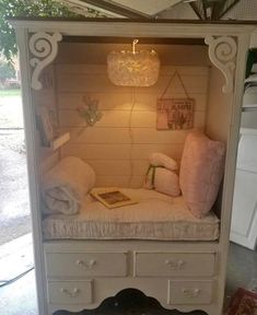a white cabinet with some pillows on top of it and a light in the corner