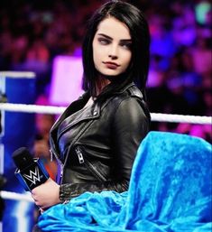 a woman in black leather jacket standing next to a wrestling ring with a blue blanket