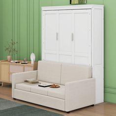 a living room with green walls and a white couch in front of a bookcase