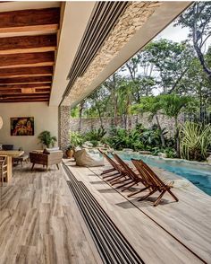 an outdoor living area with wood flooring and large windows looking out onto the pool