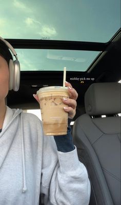 a woman wearing headphones and holding a drink in her hand