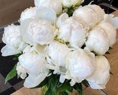 a vase filled with white flowers on top of a wooden table