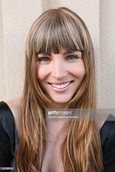 a smiling woman with long hair and bangs, wearing a black top smiles at the camera