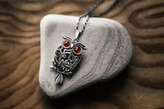 an owl with red eyes is sitting on top of a rock and has a chain around its neck