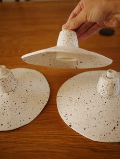 two white plates with black speckles on them being held by someone's hand