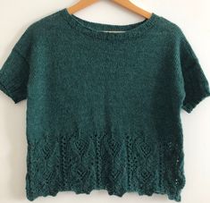 a green sweater hanging on a wooden hanger