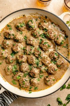 a pan filled with meatballs covered in gravy and garnished with parsley