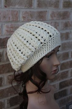 a mannequin head wearing a white crochet hat on top of a brick wall