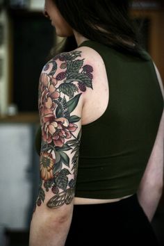 a woman's arm with flowers on it and a green tank top in the background