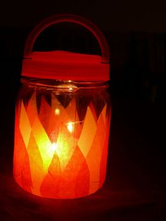 a lit candle in a glass jar on a dark surface with the lid open and lights shining brightly