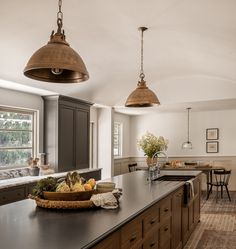 a large kitchen with an island in the middle and two pendant lights hanging from the ceiling