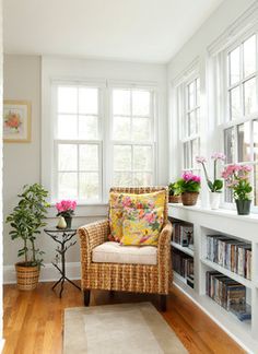 a living room filled with lots of furniture and flowers on top of a window sill