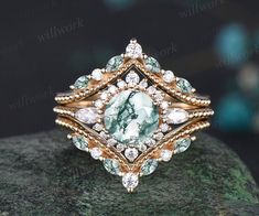 a green and white diamond ring on top of a rock