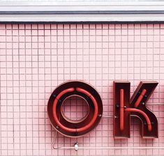 a pink wall with a neon sign that says ok and the word okay on it