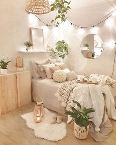 a white bedroom with plants and lights on the wall above the bed, along with other decor items