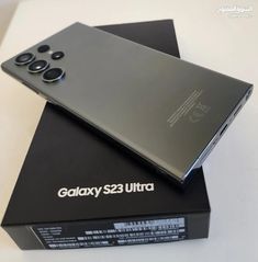 the back side of a black phone on top of a box with it's lid open