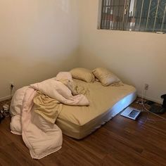 an unmade bed sitting on top of a hard wood floor