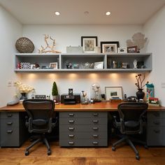 an office area with two desks, shelves and pictures on the wall above them