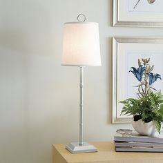 a lamp on a table next to a potted plant and some books in a room