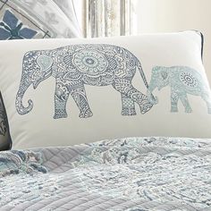 an elephant pillow sitting on top of a bed next to a blue and white comforter