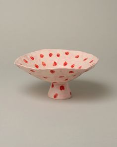 a white bowl with red polka dots on the rim and bottom, sitting on a gray surface