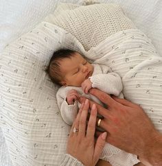 a man holding a baby in his arms while laying on top of a white blanket