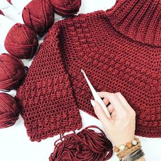 a woman is knitting and crocheting red sweaters with yarn on the table