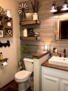 a white toilet sitting next to a sink in a bathroom under two wooden shelvings