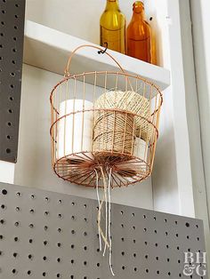 a birdcage hanging from the side of a wall with bottles in the background