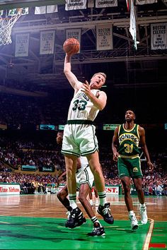 a basketball player jumping up to dunk the ball in front of two other players