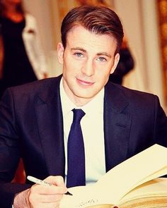 a man in a suit and tie sitting at a table with an open book