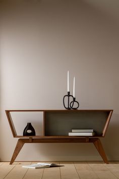 a table with two candles on it and some books in front of the top shelf