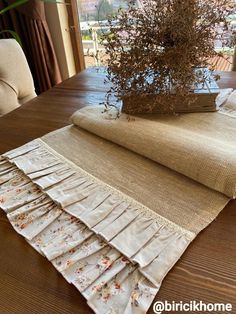 the table is covered with burlap and has a flower pot on top of it