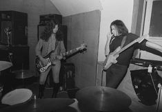 black and white photograph of two women playing guitars in a room with other musical instruments
