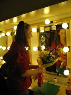 a woman standing in front of a mirror holding flowers