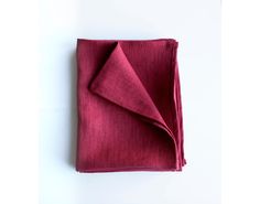 a folded napkin on a white surface with a red cloth draped over it's edge