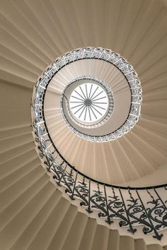 a spiral staircase with wrought iron railings and a circular glass ceiling light in the center