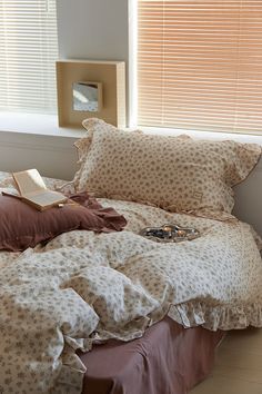 an unmade bed with two pillows and a book on the pillowcase next to it