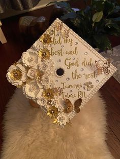 a graduation cap with flowers and butterflies on it sitting on top of a fur rug