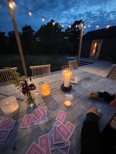 a person sitting at a table with playing cards on it and candles in front of them