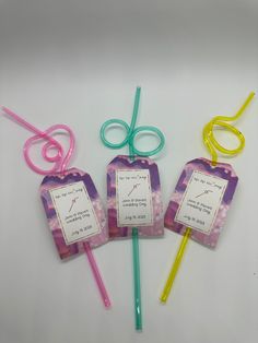 four different colored lollipop sticks with tags attached to them and some writing on them