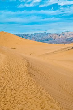 a person riding a horse on top of a sandy hill with mountains in the background