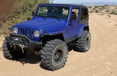 a blue jeep driving down a dirt road