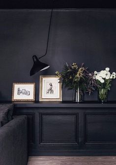 a living room with black walls and flowers in vases on the table next to it