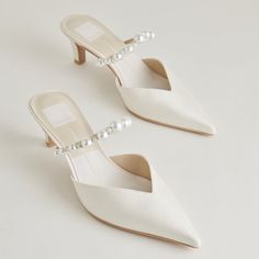 a pair of white shoes with pearls on the heel