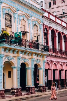 two people walking down the street in front of colorful buildings with balconies and balconyes